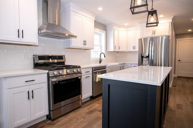 kitchen with stainless steel appliances, wall chimney exhaust hood, dark wood finished floors, light countertops, and recessed lighting