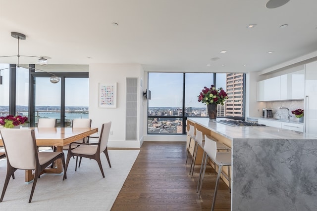 dining area featuring wood-type flooring, a wall of windows, and a water view