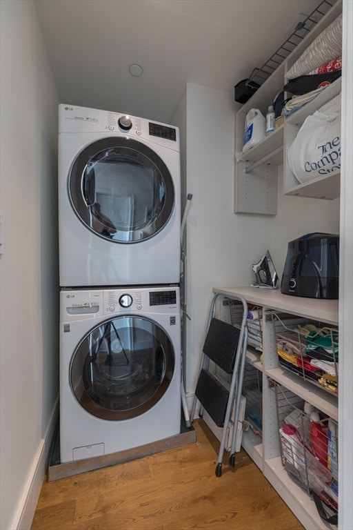 laundry area featuring light hardwood / wood-style flooring and stacked washing maching and dryer