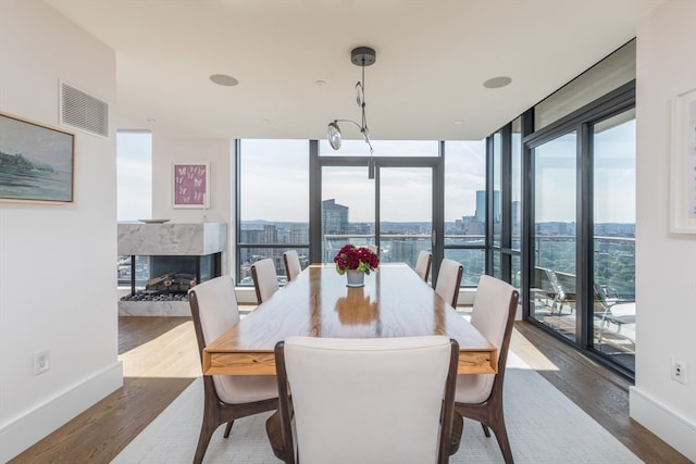 dining space featuring wood-type flooring, a fireplace, and floor to ceiling windows