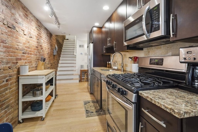 750 E 4th Unit 1, Boston, MA 02127 - kitchen featuring stainless steel appliances, a sink, light wood finished floors, dark brown cabinets, and brick wall