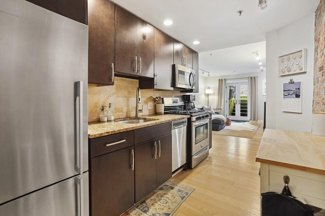 750 E 4th Unit 1, Boston, MA 02127 - kitchen with stainless steel appliances, a sink, light wood-style flooring, dark brown cabinetry, and decorative backsplash