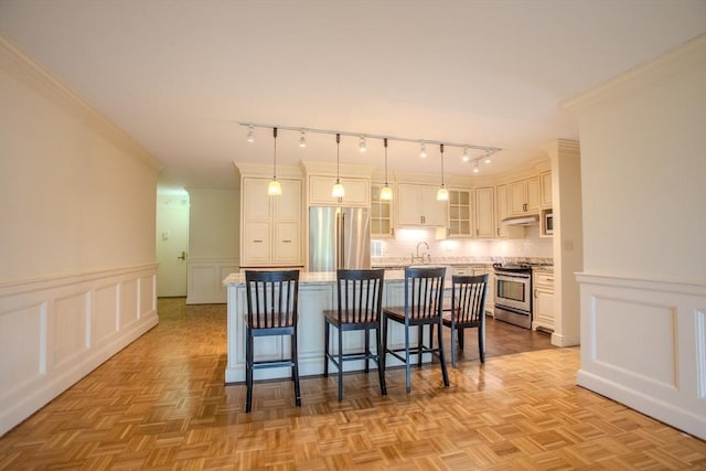 111 Perkins St Unit 42, Boston, MA 02130 - kitchen with appliances with stainless steel finishes, a decorative wall, a kitchen bar, track lighting, and a kitchen island