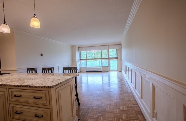 111 Perkins St Unit 42, Boston, MA 02130 - kitchen featuring ornamental molding, cream cabinetry, a decorative wall, a breakfast bar area, and wainscoting