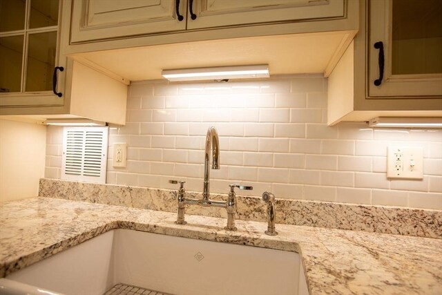 111 Perkins St Unit 42, Boston, MA 02130 - kitchen with a sink, glass insert cabinets, decorative backsplash, light stone counters, and cream cabinetry