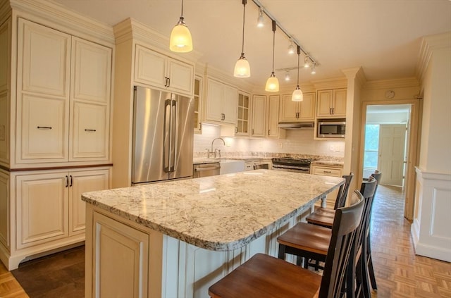 111 Perkins St Unit 42, Boston, MA 02130 - kitchen featuring appliances with stainless steel finishes, light stone counters, glass insert cabinets, backsplash, and a kitchen breakfast bar