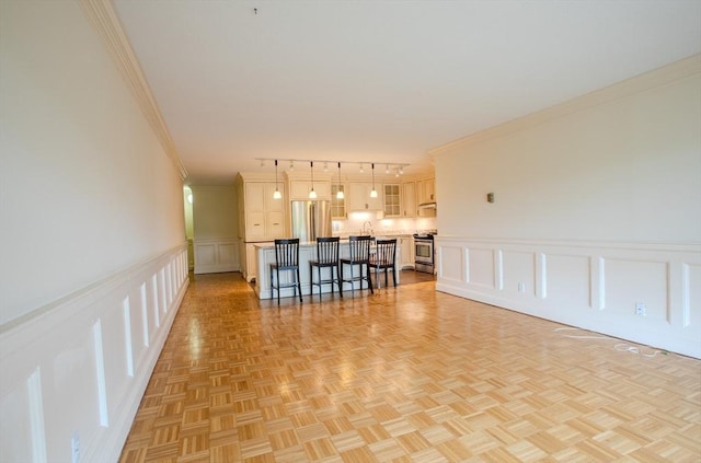 111 Perkins St Unit 42, Boston, MA 02130 - unfurnished living room with a decorative wall, crown molding, rail lighting, and a wainscoted wall