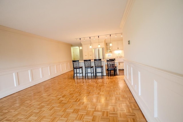 111 Perkins St Unit 42, Boston, MA 02130 - kitchen featuring freestanding refrigerator, a breakfast bar area, crown molding, a decorative wall, and white cabinetry