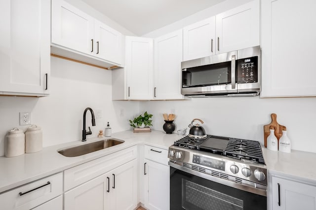 kitchen featuring white cabinetry, sink, light stone countertops, and appliances with stainless steel finishes