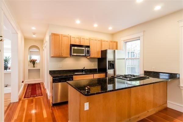 8 Fainwood Cir Unit 2, Cambridge, MA 02139 - kitchen with appliances with stainless steel finishes, a peninsula, dark wood-style flooring, dark stone countertops, and baseboards