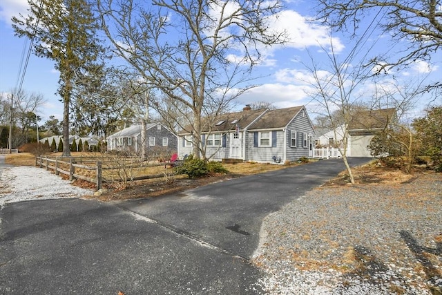 view of front facade with aphalt driveway, a residential view, a chimney, and fence