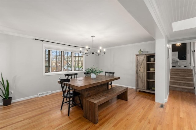 dining room with stairway, crown molding, a skylight, light wood-style floors, and visible vents