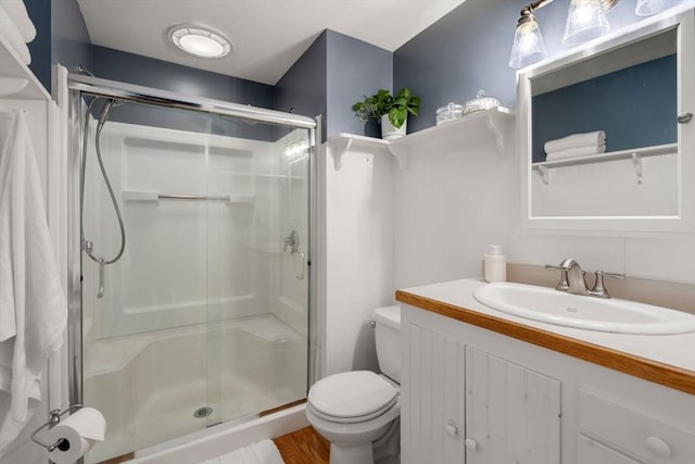 full bathroom featuring a shower stall, toilet, vanity, and wood finished floors