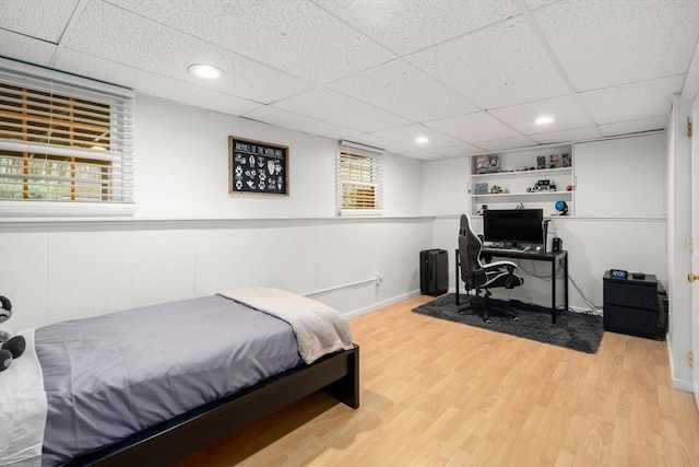 bedroom with light wood-style floors and a drop ceiling