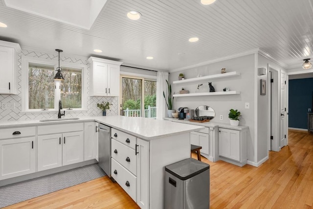 kitchen featuring white cabinets, dishwasher, a sink, and tasteful backsplash