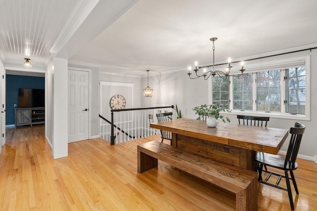 dining area with baseboards, light wood-style floors, a notable chandelier, and ornamental molding