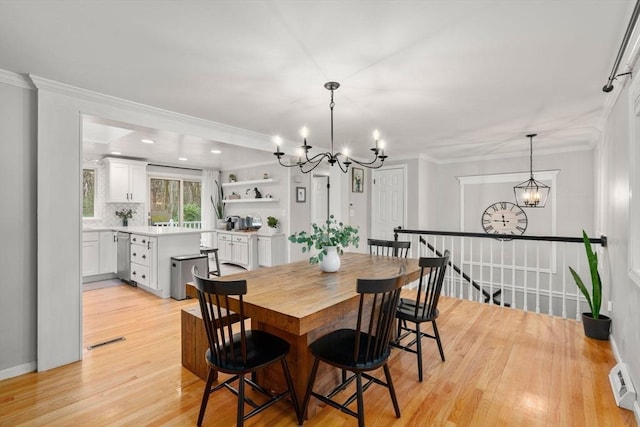 dining room with ornamental molding, visible vents, light wood finished floors, and a notable chandelier