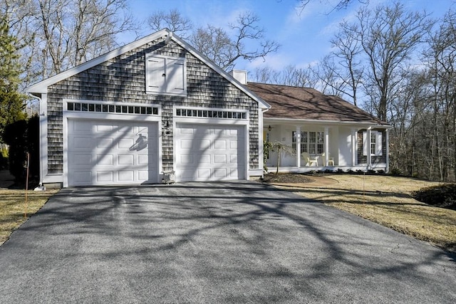 view of front of home featuring aphalt driveway, covered porch, an attached garage, and a chimney