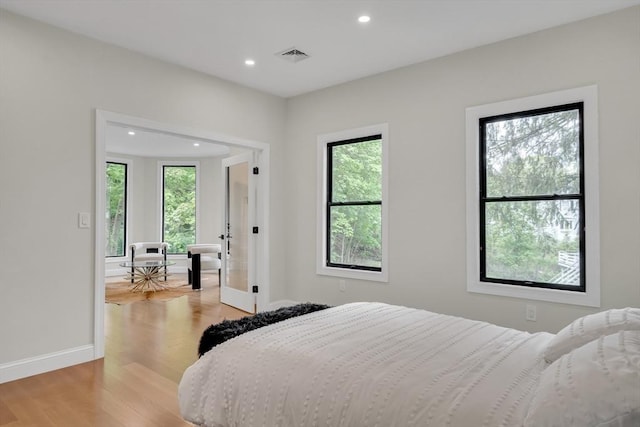 bedroom with recessed lighting, multiple windows, light wood-style flooring, baseboards, and french doors