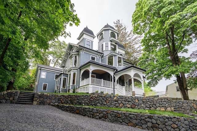 victorian home featuring covered porch and stairway