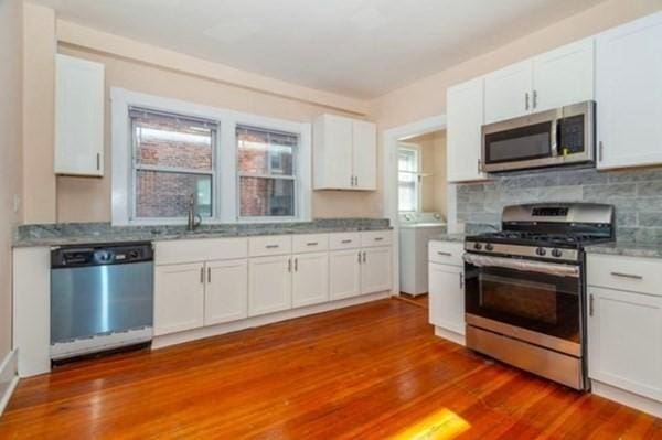 kitchen featuring tasteful backsplash, dark wood-style flooring, white cabinets, stainless steel appliances, and a sink