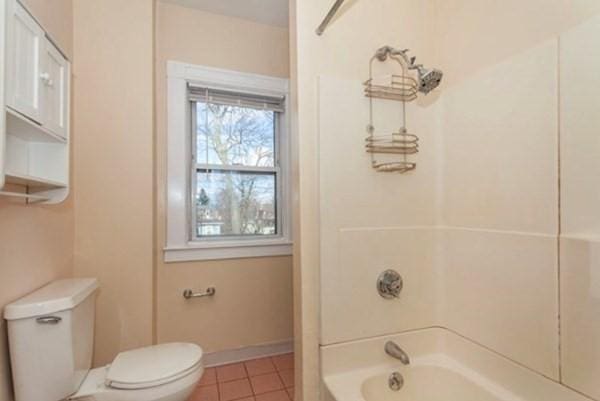 full bathroom with shower / bathing tub combination, baseboards, toilet, and tile patterned flooring