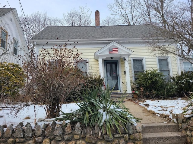 view of front of property featuring a chimney and roof with shingles