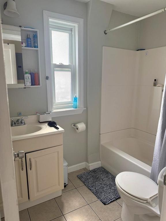 bathroom with tile patterned floors, toilet, shower / tub combo, and baseboards