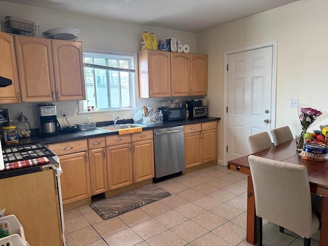 kitchen featuring light brown cabinets, light tile patterned floors, a sink, dark countertops, and stainless steel appliances