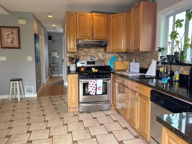 kitchen with a sink, stainless steel appliances, visible vents, under cabinet range hood, and tasteful backsplash