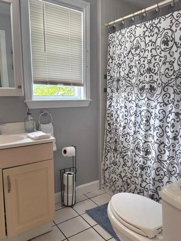full bathroom with toilet, a shower with shower curtain, baseboards, tile patterned flooring, and vanity