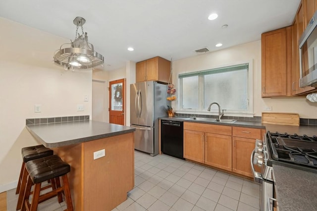 kitchen with kitchen peninsula, a breakfast bar, stainless steel appliances, sink, and hanging light fixtures