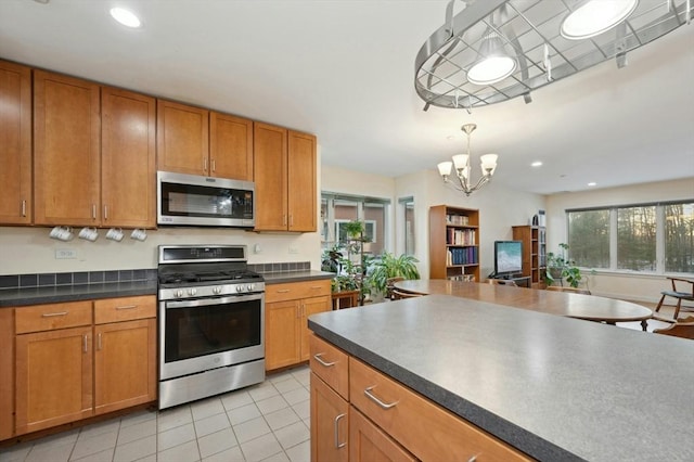 kitchen with a chandelier, appliances with stainless steel finishes, decorative light fixtures, and light tile patterned floors