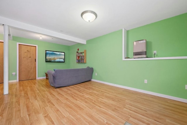 unfurnished living room featuring beam ceiling and light hardwood / wood-style floors