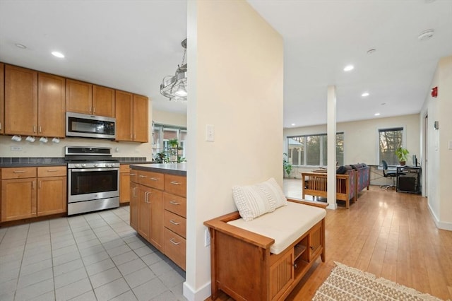 kitchen featuring pendant lighting, stainless steel appliances, and light hardwood / wood-style flooring