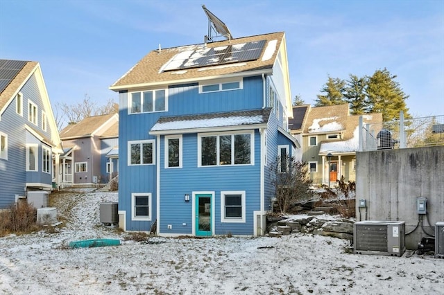 snow covered rear of property with solar panels and central AC