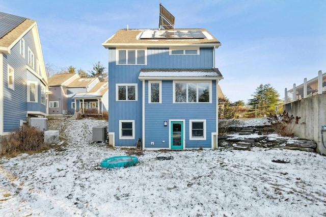 snow covered back of property with solar panels and cooling unit