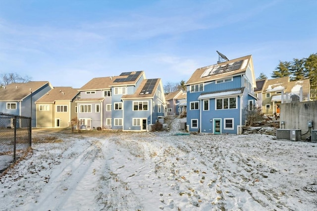 snow covered house featuring central AC unit and solar panels