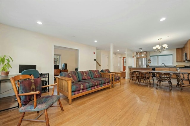 living room with sink, light hardwood / wood-style floors, and an inviting chandelier