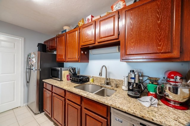 kitchen featuring light stone countertops, sink, light tile patterned floors, and stainless steel appliances