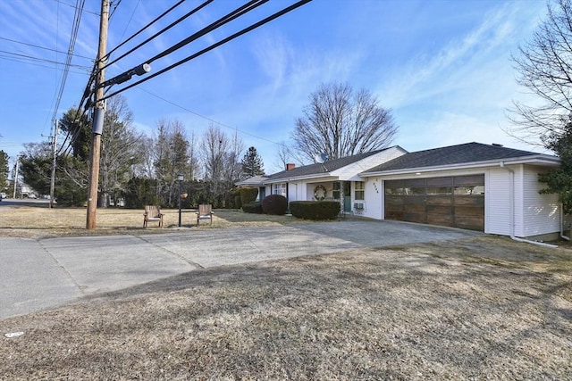 exterior space with driveway, a chimney, and an attached garage