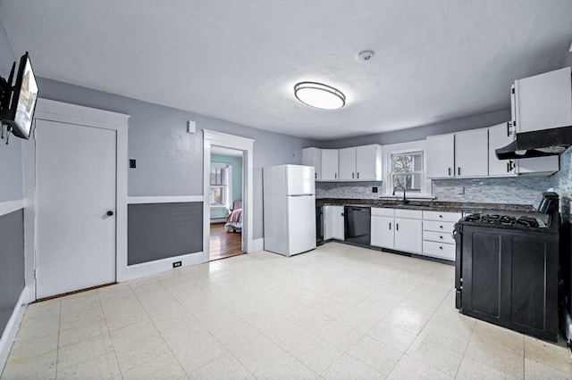 kitchen with freestanding refrigerator, dark countertops, dishwasher, a sink, and range with gas cooktop
