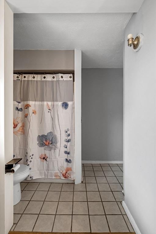 full bathroom with toilet, tile patterned floors, and a shower with shower curtain