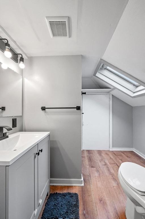 bathroom with vanity, visible vents, wood finished floors, and baseboards