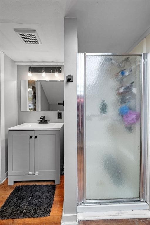 full bathroom featuring visible vents, wood finished floors, a shower stall, and vanity