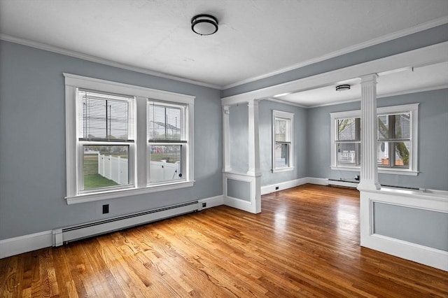 spare room with baseboard heating, ornate columns, and wood finished floors