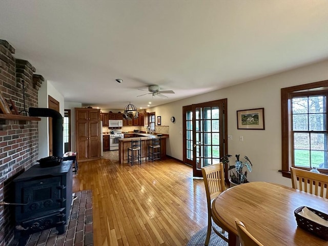 32 Machipscat Trl, West Tisbury, MA 02575 - dining room with a ceiling fan, a wood stove, light wood finished floors, and baseboards