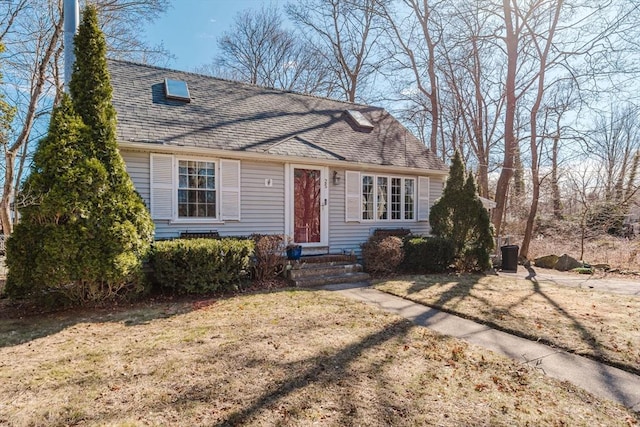 cape cod home with a shingled roof and a front lawn