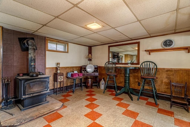 73 Spur Rd, Dover, NH 03820 - dining area featuring tile patterned floors, wainscoting, a paneled ceiling, a wood stove, and wood walls