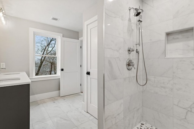 bathroom featuring vanity, visible vents, baseboards, marble finish floor, and tiled shower